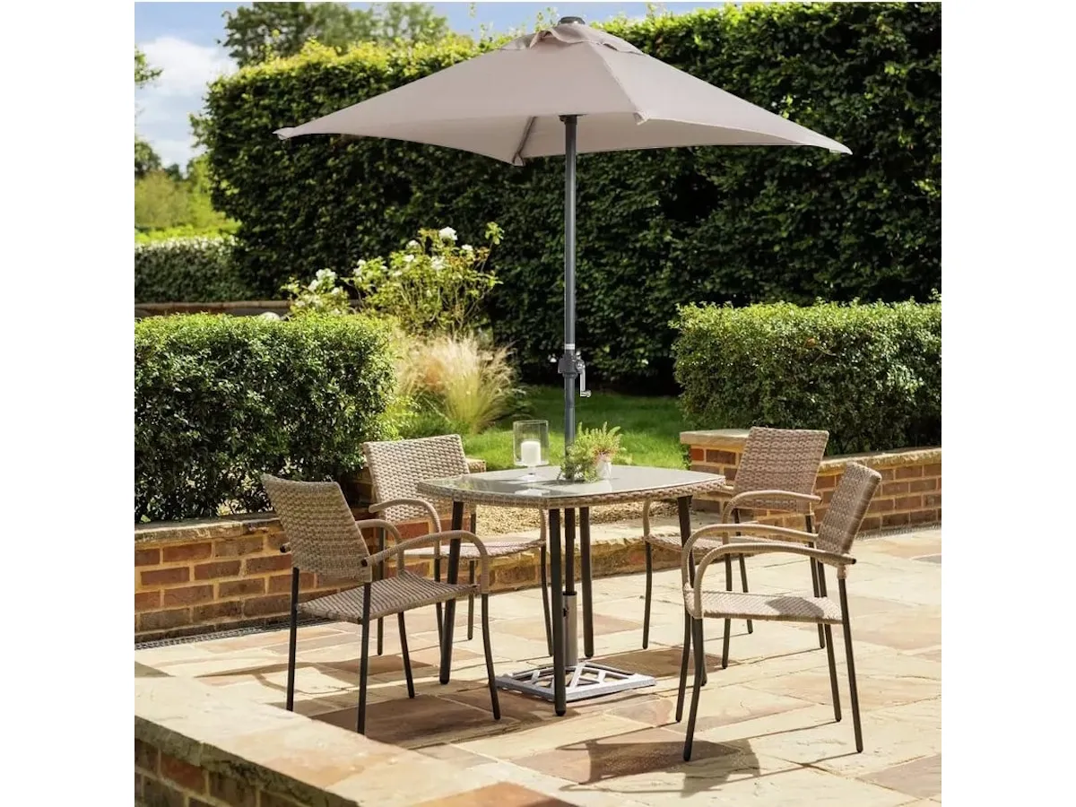 Glass-topped outdoor dining table, 4 rattan chairs and a natural coloured parasol