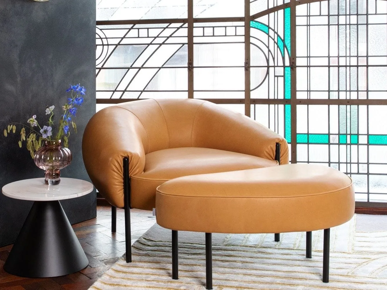 Curved brown leather chair and footstool