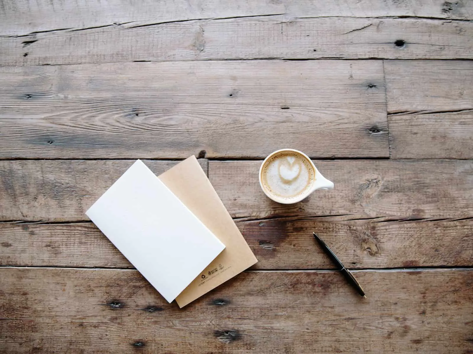 Bare wooden floor with a cup of coffee and a blank notebook