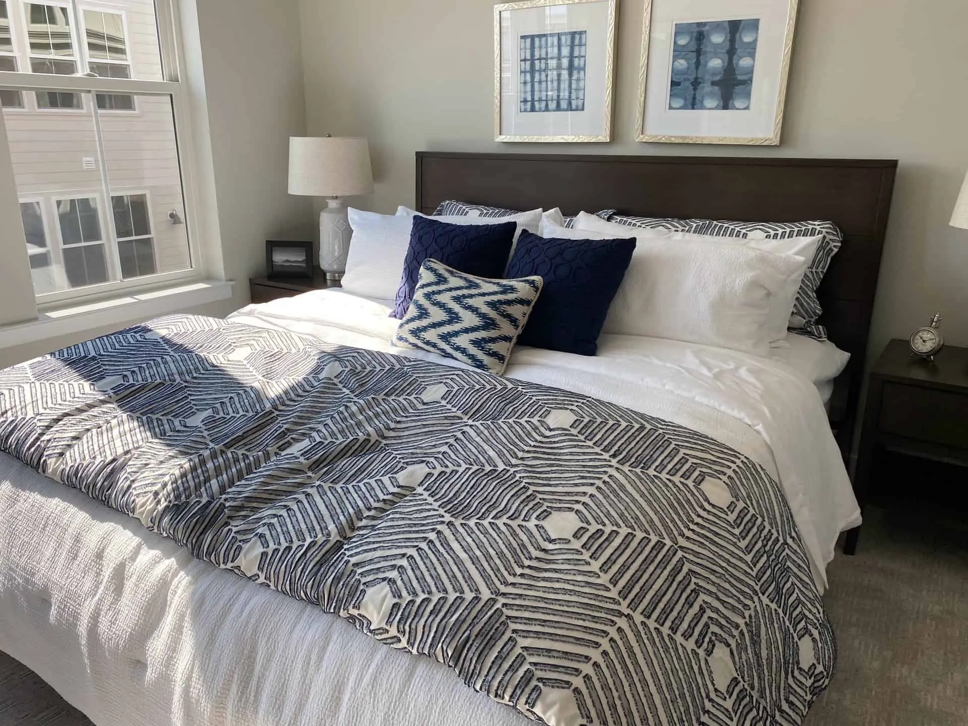 Bed with navy patterened throw and grey headboard