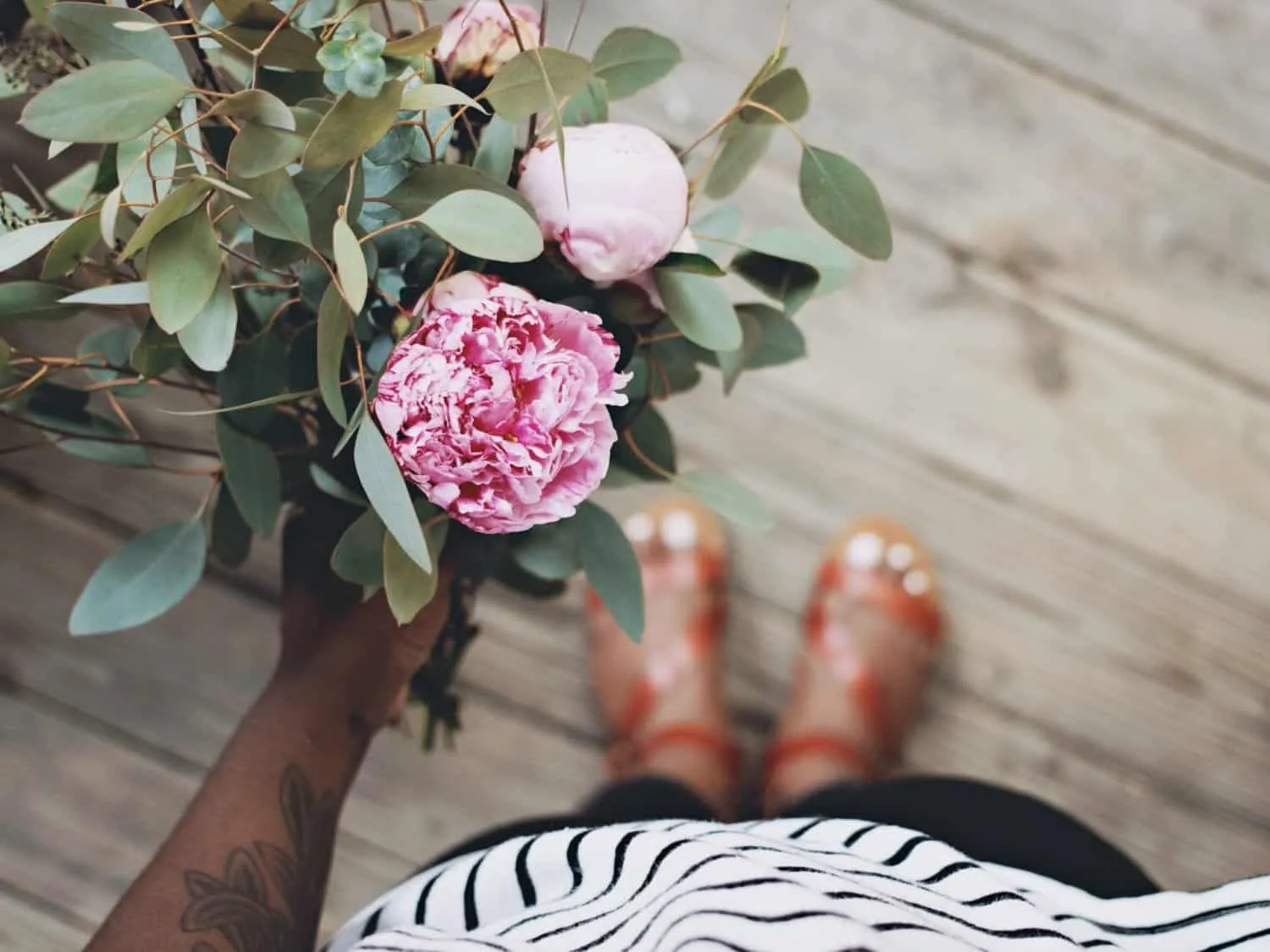 Stood on a wooden floor with a pink flower