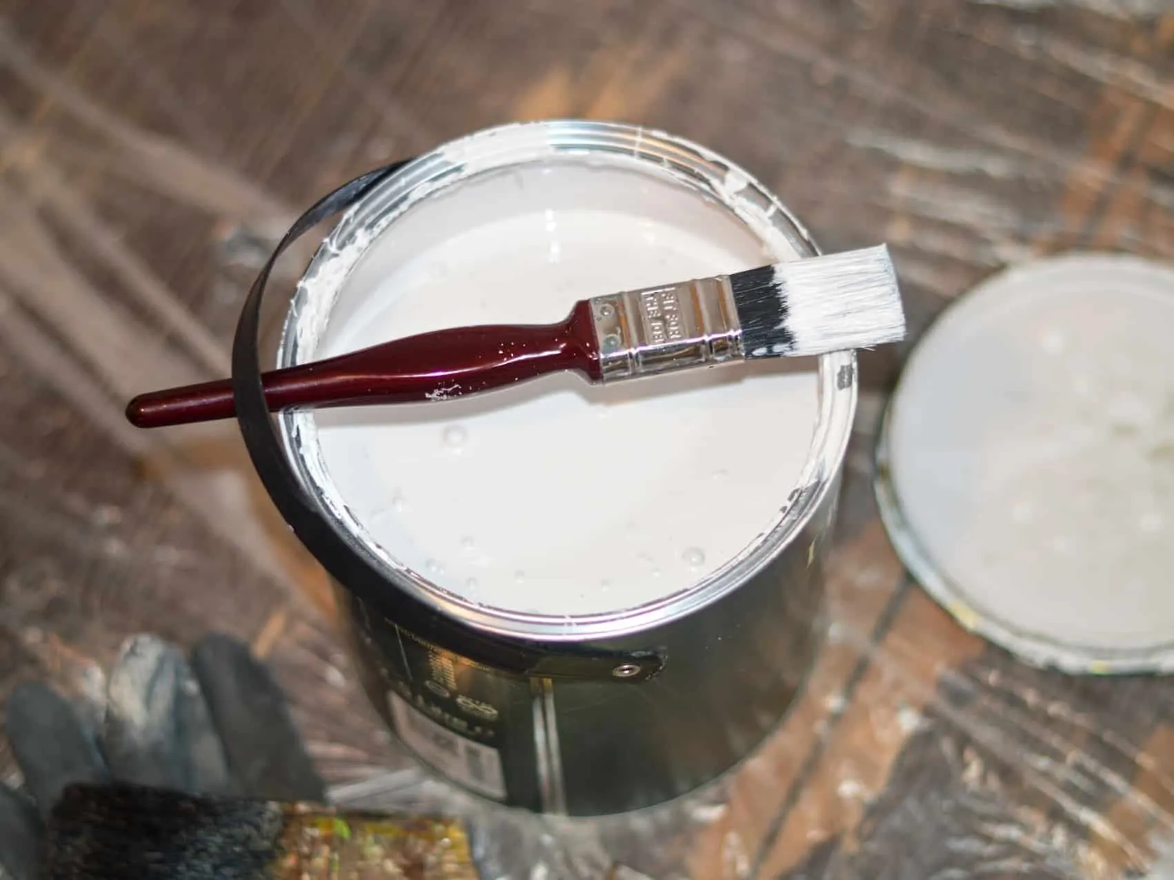Tin of white paint and a small paintbrush