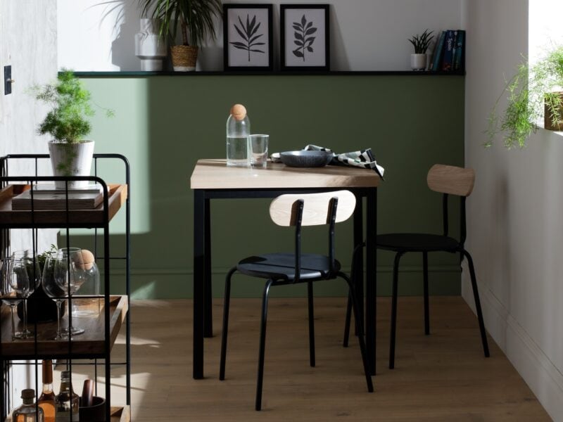 Small square dining table with a wood-effect top and black frame with a pair of matching chairs