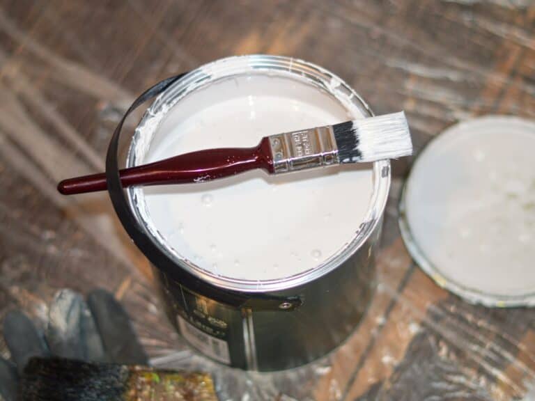 Tin of white paint and a small paintbrush