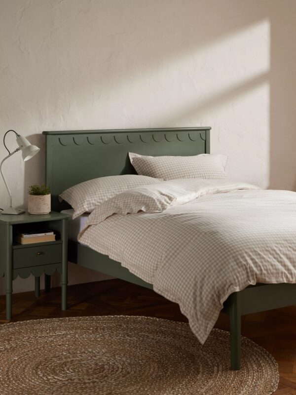 Green-painted bed frame with scalloped detailing